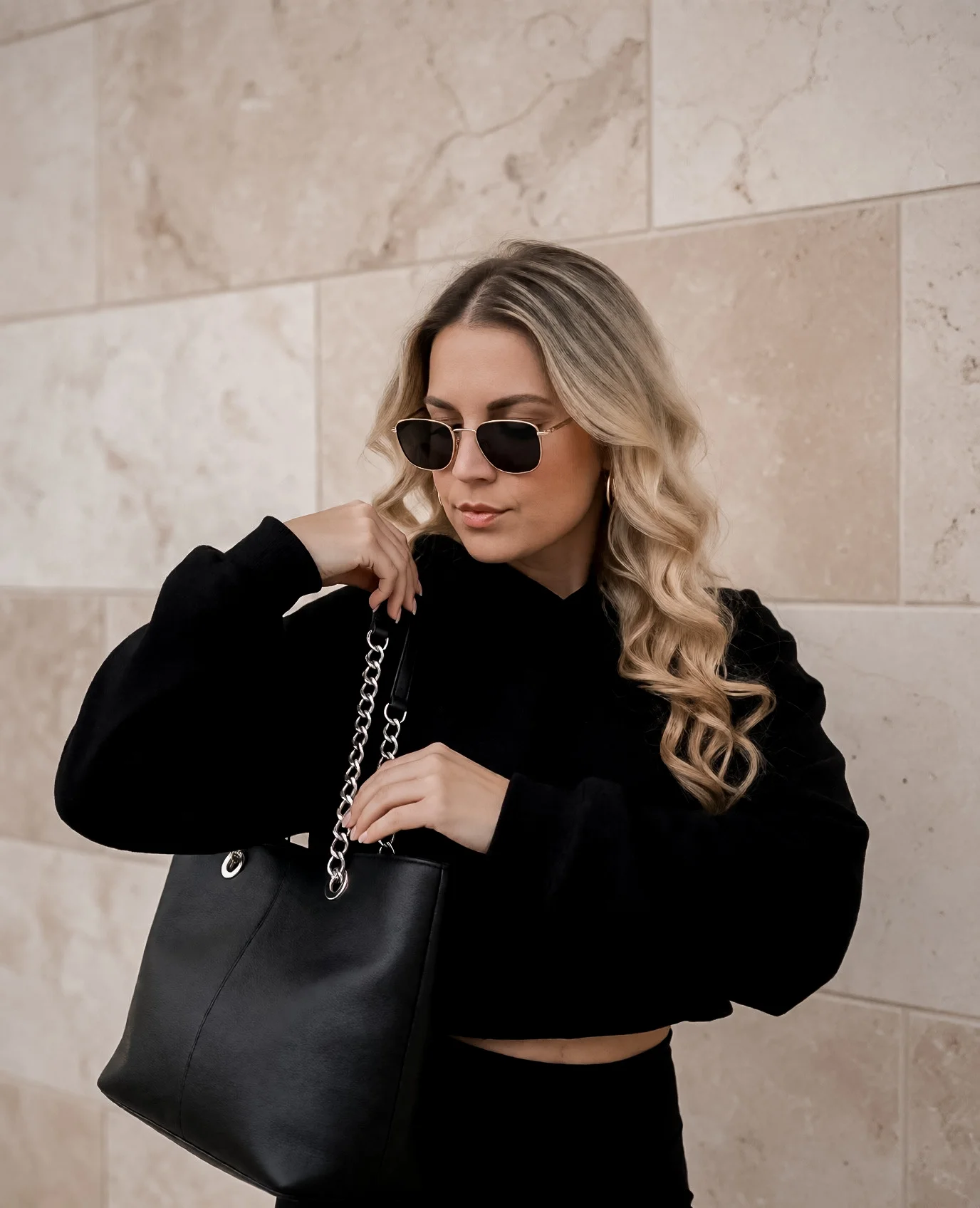 Ella Maria in a black outfit against a neutral stone wall